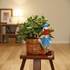 A decorative ceramic figurine of Donald Duck in a blue sailor outfit holding a hoe, standing beside a brown wooden bucket on a small wooden stool.