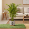 A cylindrical ceramic planter with a textured off-white body, featuring a black geometric patterned oval emblem on the front and a gold-toned base, set on artificial green turf.