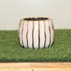 Ceramic pot with gold stripes on a green mat