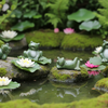 Four green frog figurines in different poses arranged on a strip of artificial grass against a plain light background.