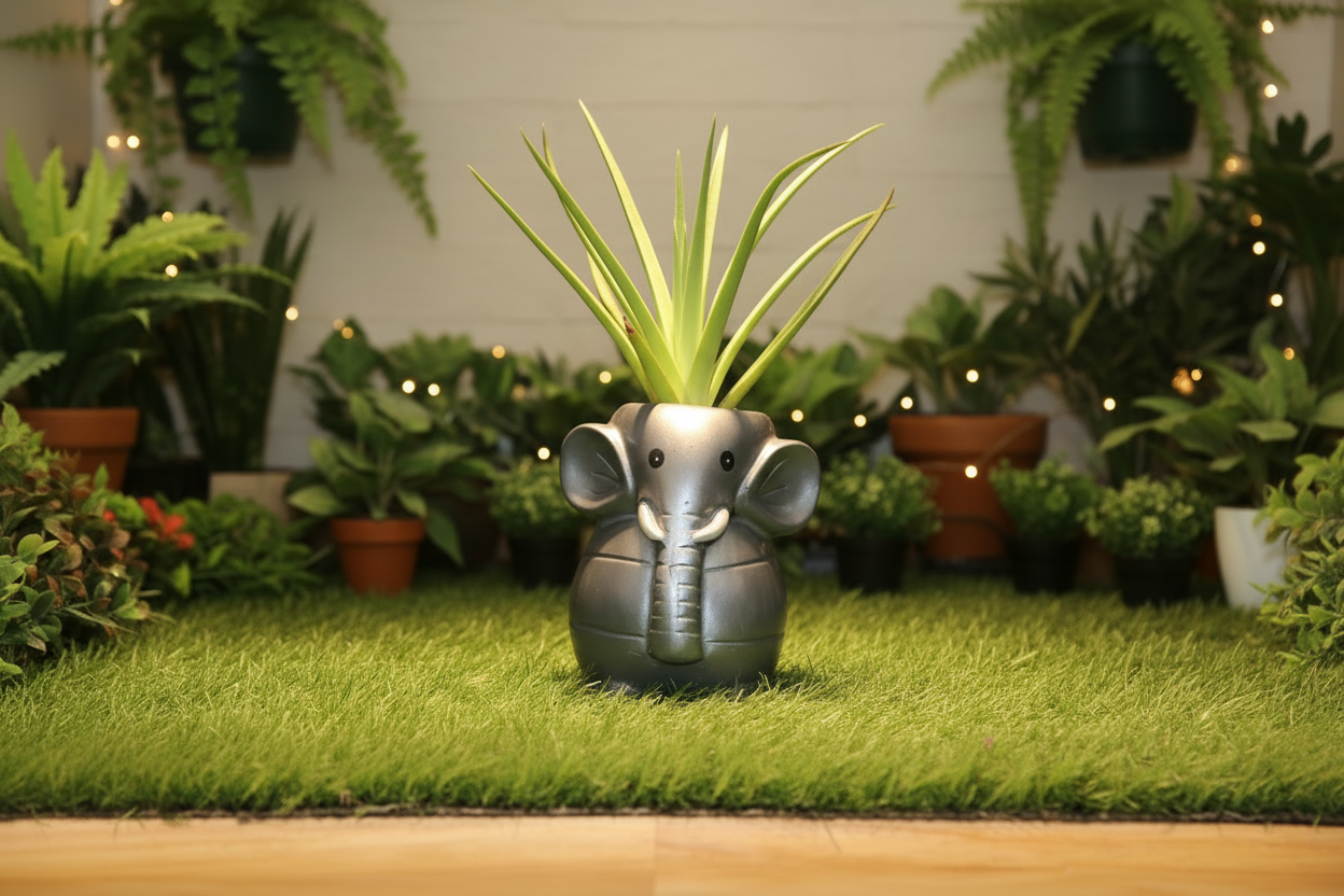 A dark gray elephant-shaped container or planter sitting on a strip of green artificial grass, with a plain off-white wall behind it.