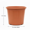 An orange-brown plastic nursery pot with a small white barcode label on the front, shown against a plain beige wall.